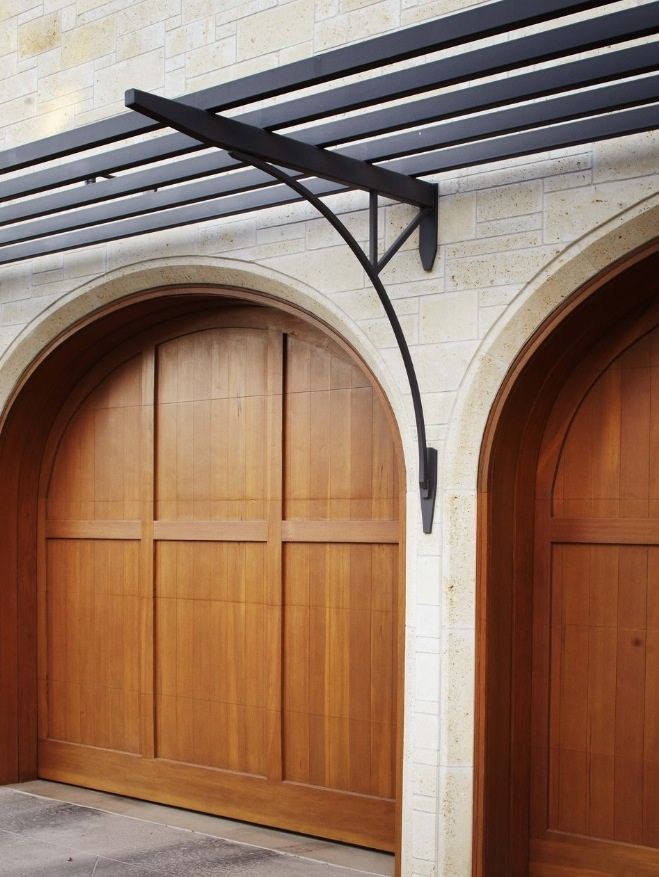 two wooden garage doors are open on the side of a brick building with arched doorways