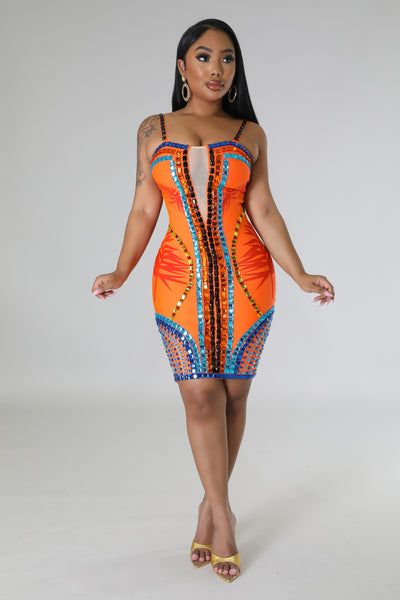 a woman in an orange and blue dress with her hands on her hips, posing for the