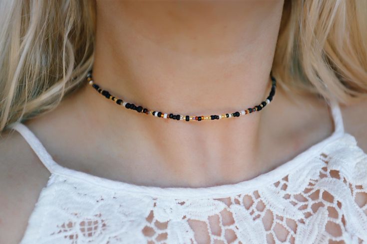 Our beautiful hand mixed seed beads with warm golds and black tones Choker is 13 inches with a 2" adjustable extender chain. 15 inches total length. Need a custom length? We are more than happy to do that for you! Please enter your custom request in the optional personalization box down below Finished with a gold plated stainless steel lobster clasp & chain. This necklace is water proof 💦  Handmade with love by Amanda Check out my shop for more chokers to layer with this one! 🧡 Black Heishi Beads Jewelry, Black Heishi Beads Necklace For Gift, Black Beaded Heishi Beads Necklace, Handmade Black Heishi Beads, Black Beads With Gold Details For Festival, Black And Gold Beads For Festival, Black Heishi Beaded Necklaces, Black Beaded Necklaces With Gold Beads For Festival, Adjustable Black Choker With Colorful Beads