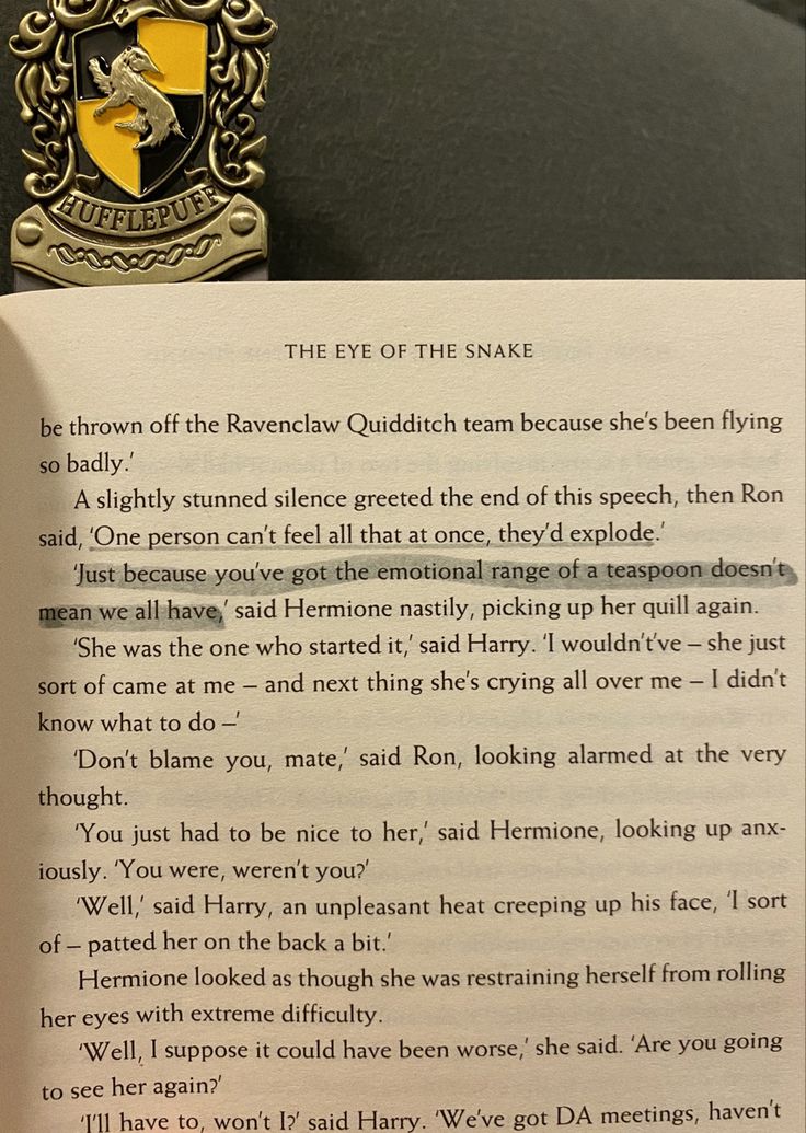 an open harry potter book with a hogwarts pin on it's cover