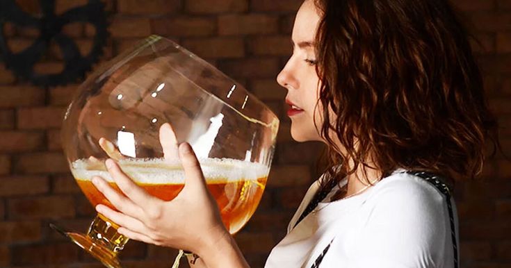 a woman holding a large glass filled with liquid