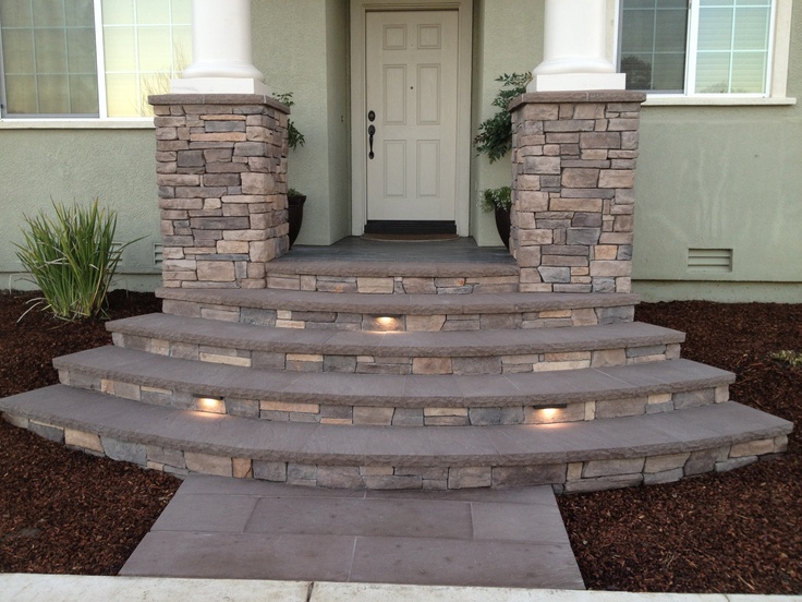 a house with steps leading up to the front door and lights on either side of it