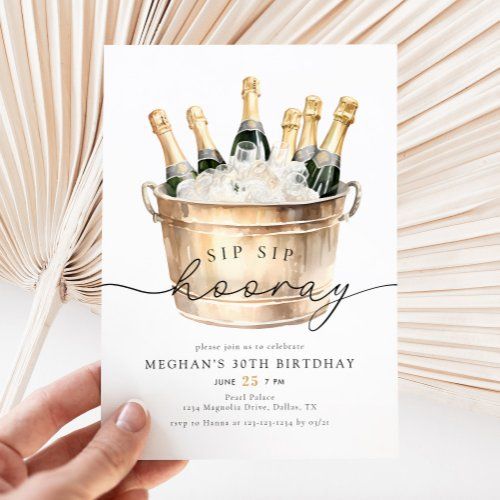 a hand holding up a birthday card with champagne in a bucket