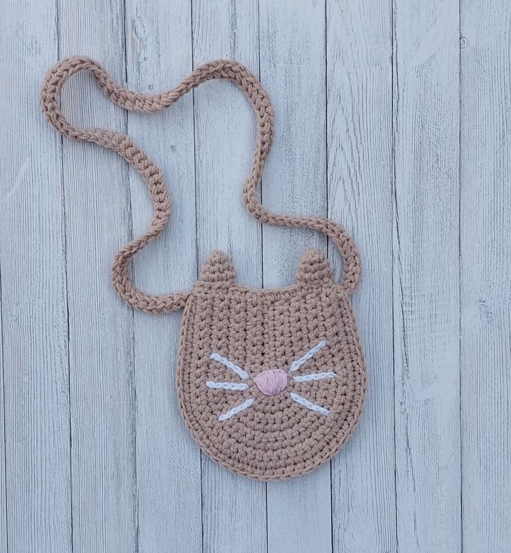 a crocheted purse with a cat face on the front, and a pink nose