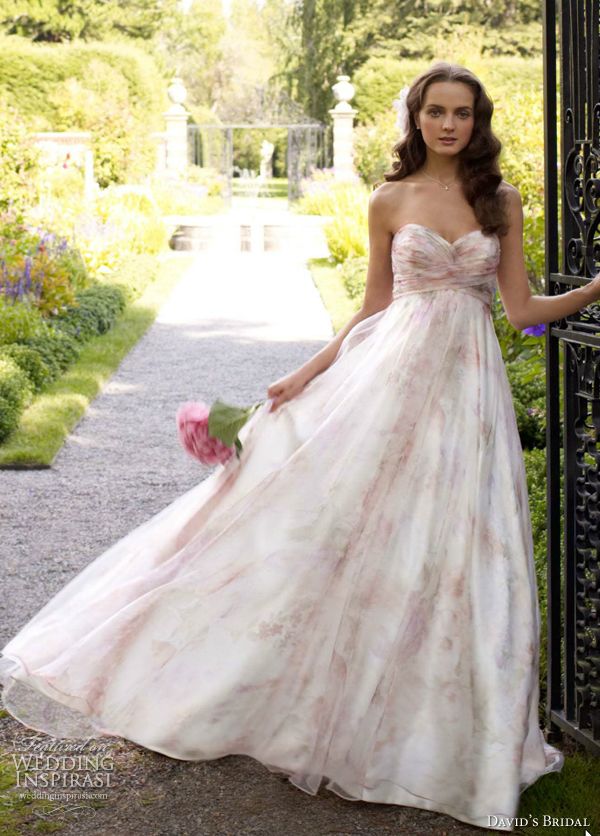 a woman in a long dress is standing by an iron gate and holding a bouquet