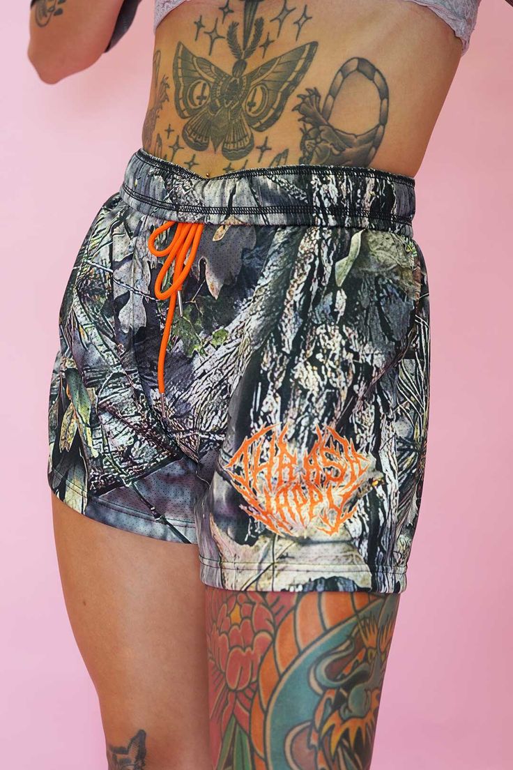 a woman with tattoos on her arms and legs is wearing shorts that have an orange string attached to the side