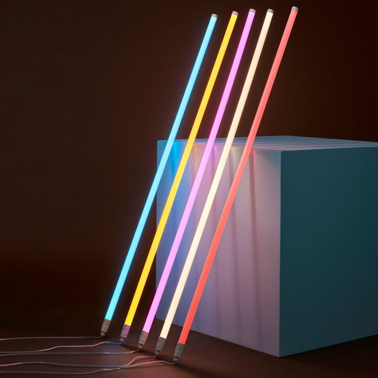 four multicolored straws sitting on top of a white box next to each other