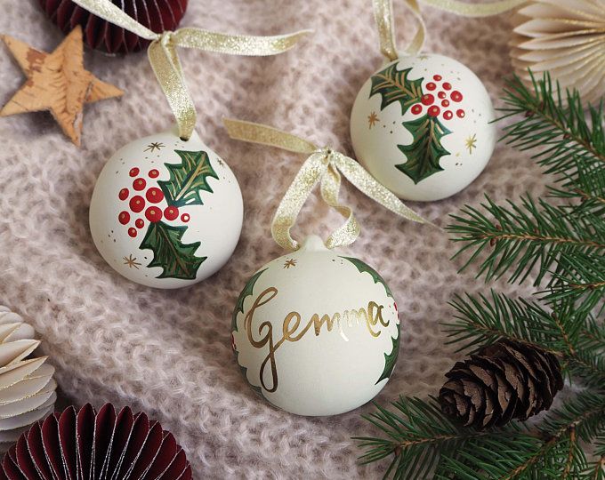 three christmas ornaments with the word germe on them next to pine cones and seashells