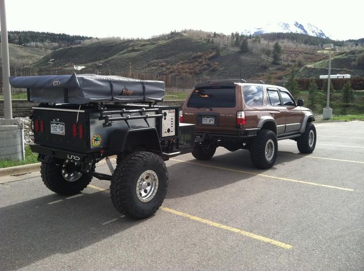 two vehicles parked next to each other in a parking lot with mountains in the background