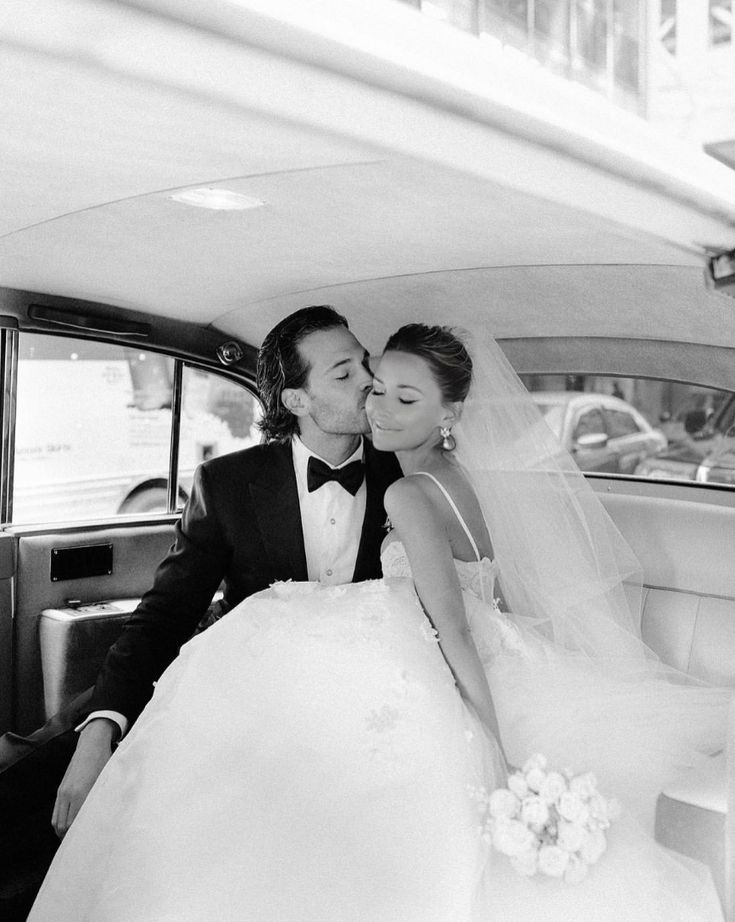 a bride and groom kissing in the back of a car