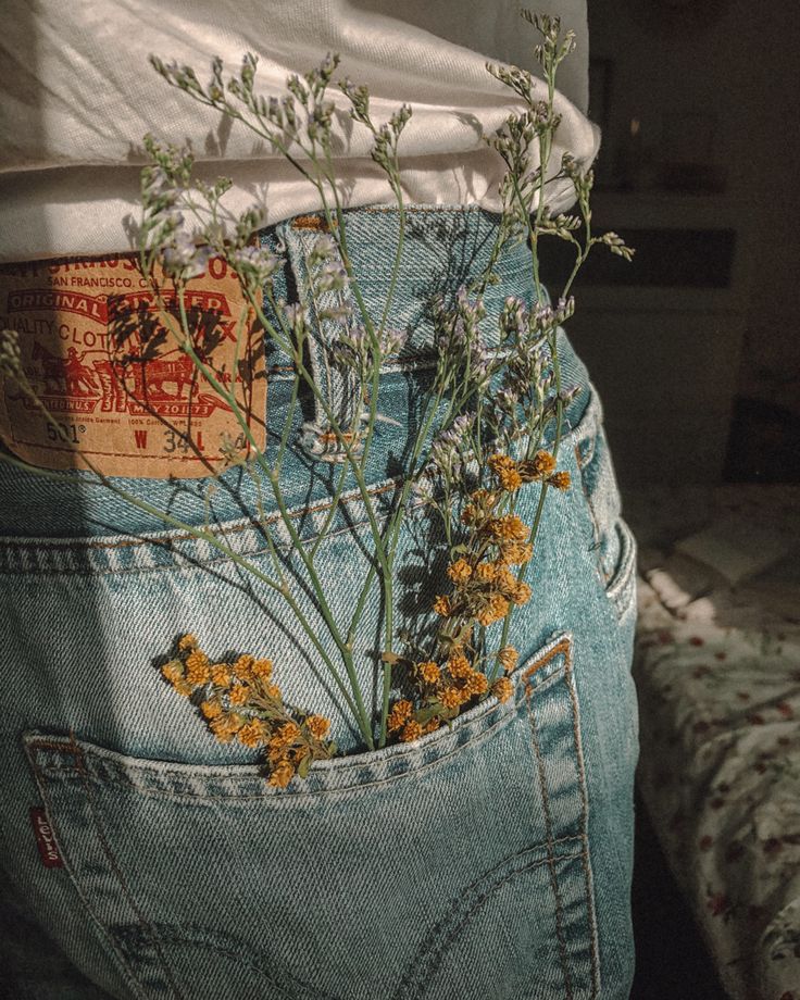 the back pocket of someone's jeans with wildflowers sticking out of it