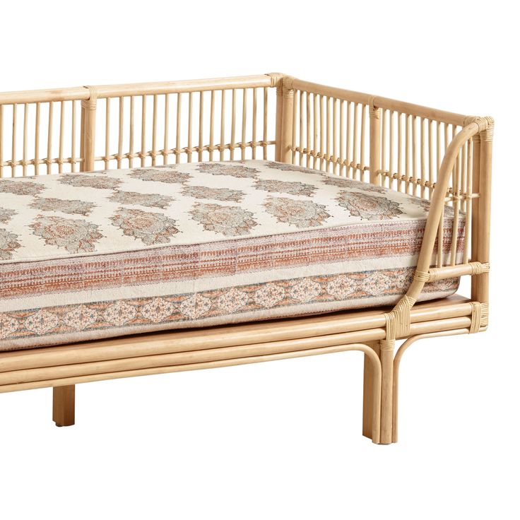 a bed made out of bamboo with a cushion on it's side and back