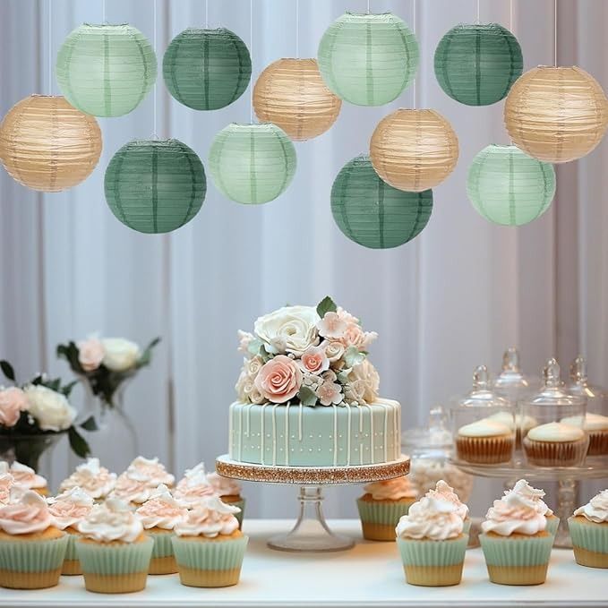 a table topped with cupcakes covered in frosting and paper lanterns hanging from the ceiling