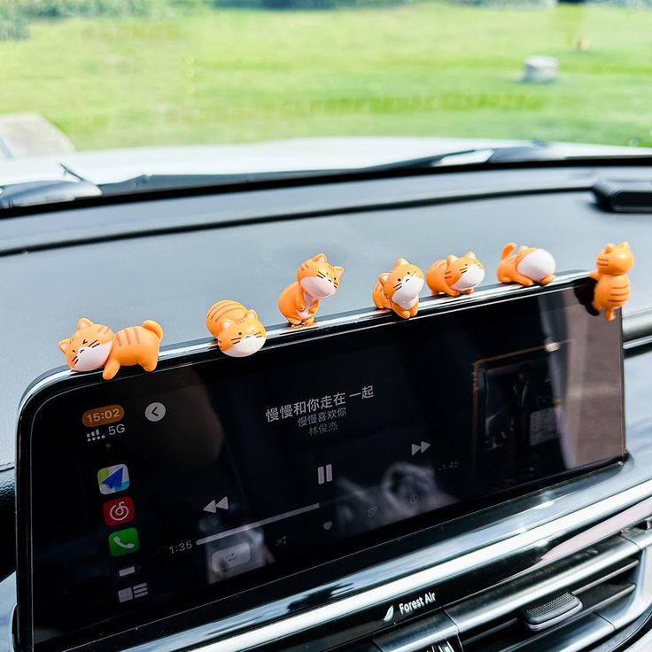 there are stuffed animals sitting on the dashboard of a cell phone holder in a car