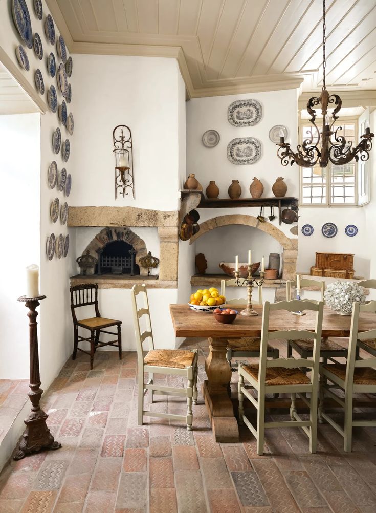 a dining room table with chairs and plates on the wall above it, next to a fireplace