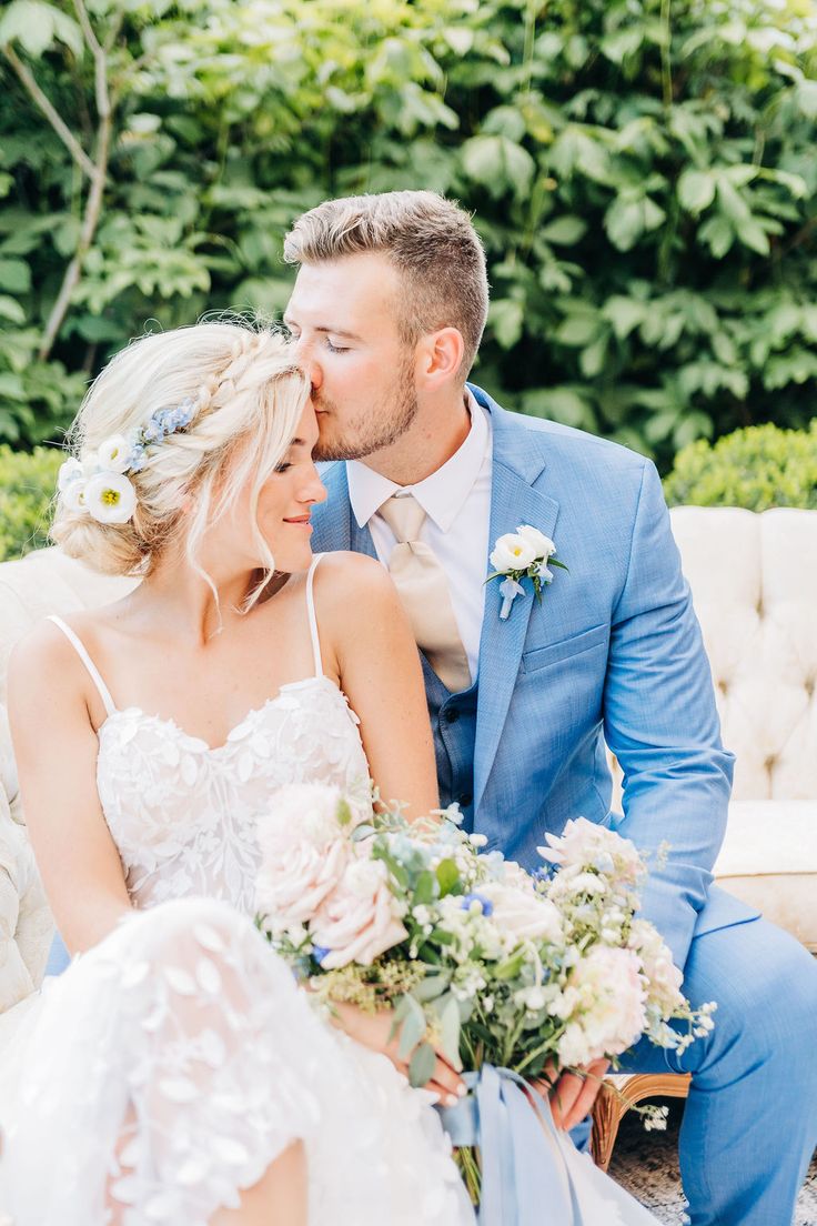 a bride and groom are sitting on a bench in front of some bushes with flowers