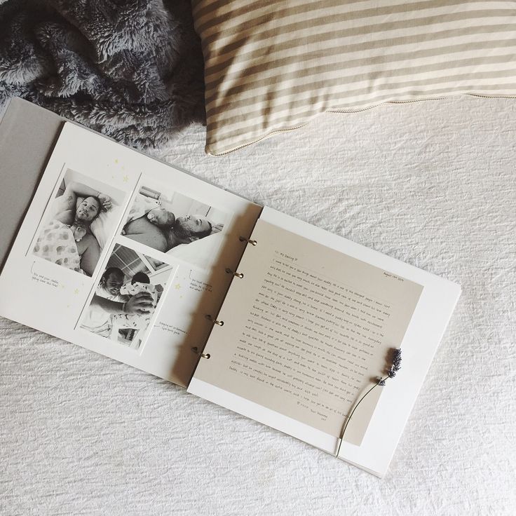 an open book sitting on top of a bed next to pillows and a pillow cover