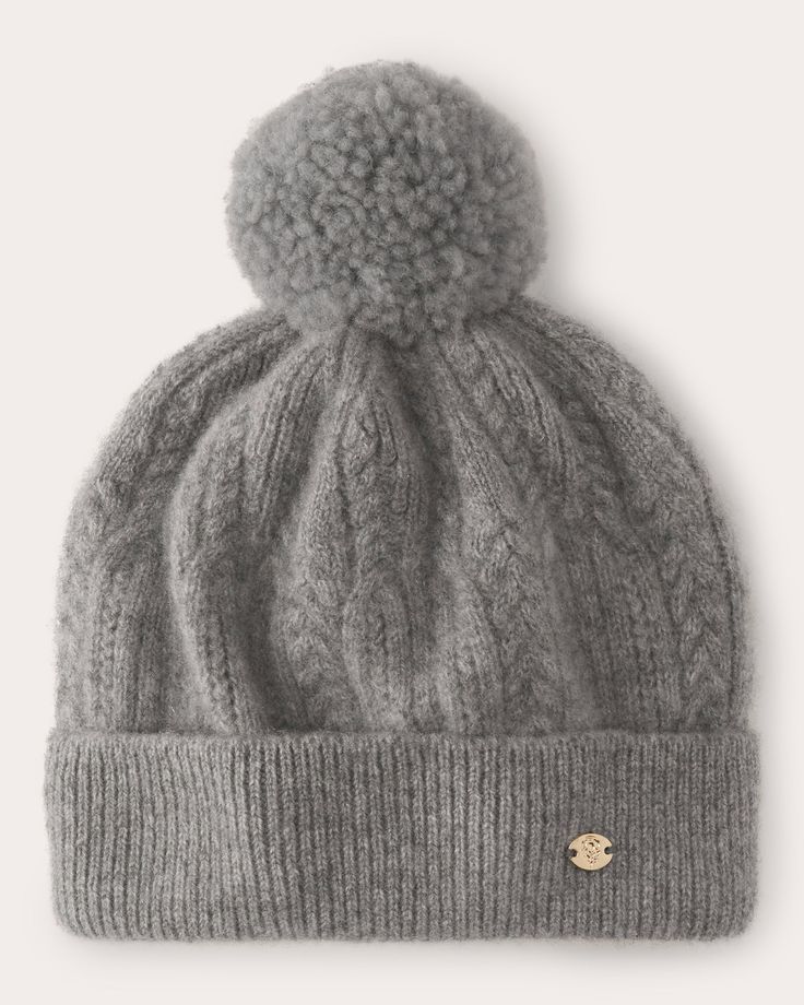 a grey hat with a pom - pom on the top and a white background