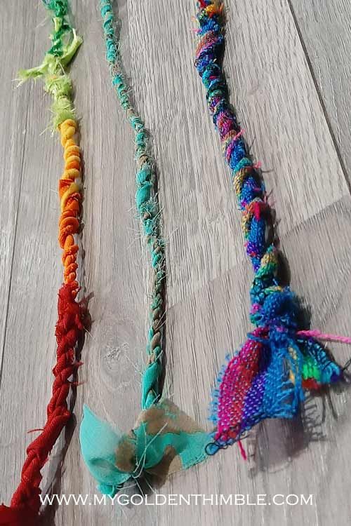 three braided necklaces are laying on the floor next to each other and one is colorful