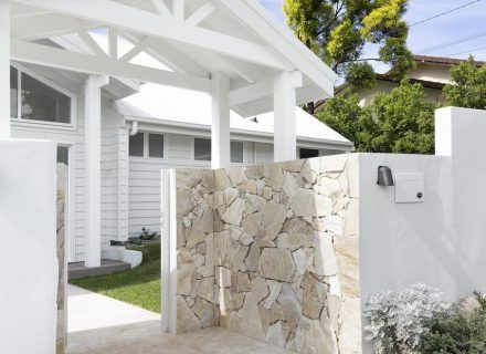 a white house with a stone wall next to it