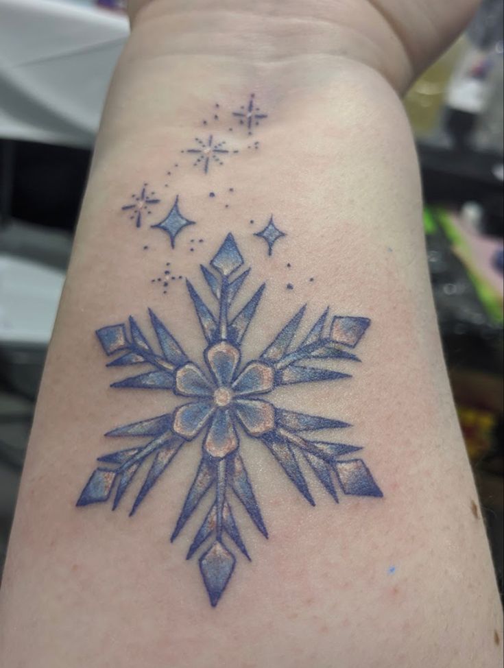 a snowflake tattoo on the back of a woman's arm, with stars in the background