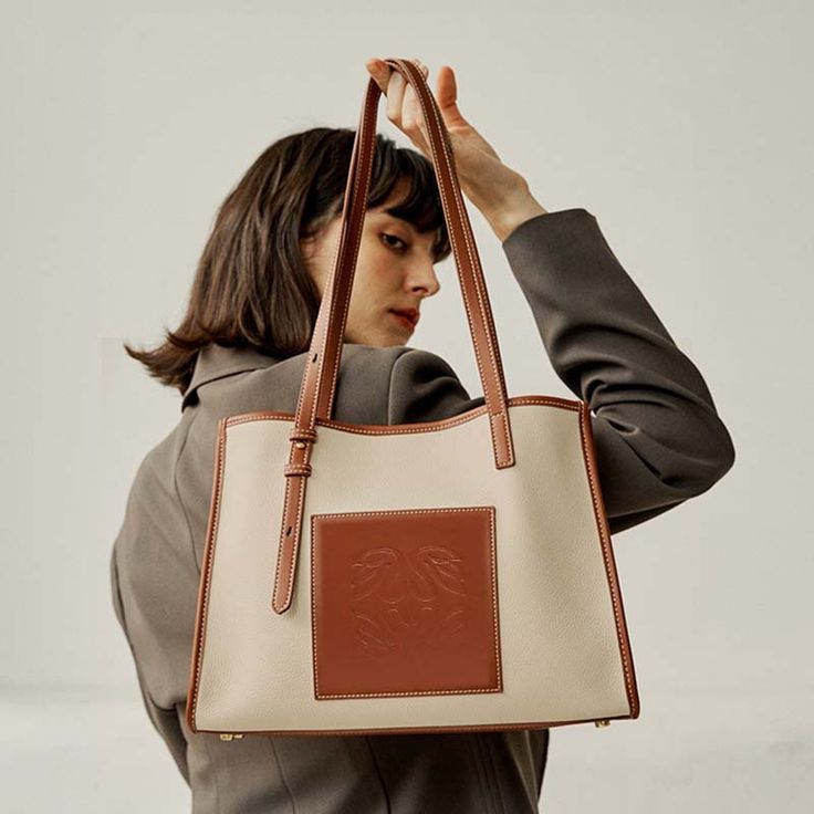 If you don't like to travel light, then our large-sized tote bag is for you. Featuring a refreshing beige finish, double top handles, and a roomy interior, this boxy tote is all class and elegance.  It's embossed a  brown patch in the front and topped with adjustable straps, it’s a style to fill with everything from your beach read and sun cream to a rolled-up picnic blanket and sunnies.Weight: 600 gWidth (cm): 10 cmHeight (cm): 25 Color: BrownInterior Material: FiberMaterial_bag: PU LeatherBagT Classic Leather Tote, Beach Read, Minimalist Women, Pu Leather Bag, Student Bag, Sun Cream, Wedding Bag, Pretty Bags, Travel Light