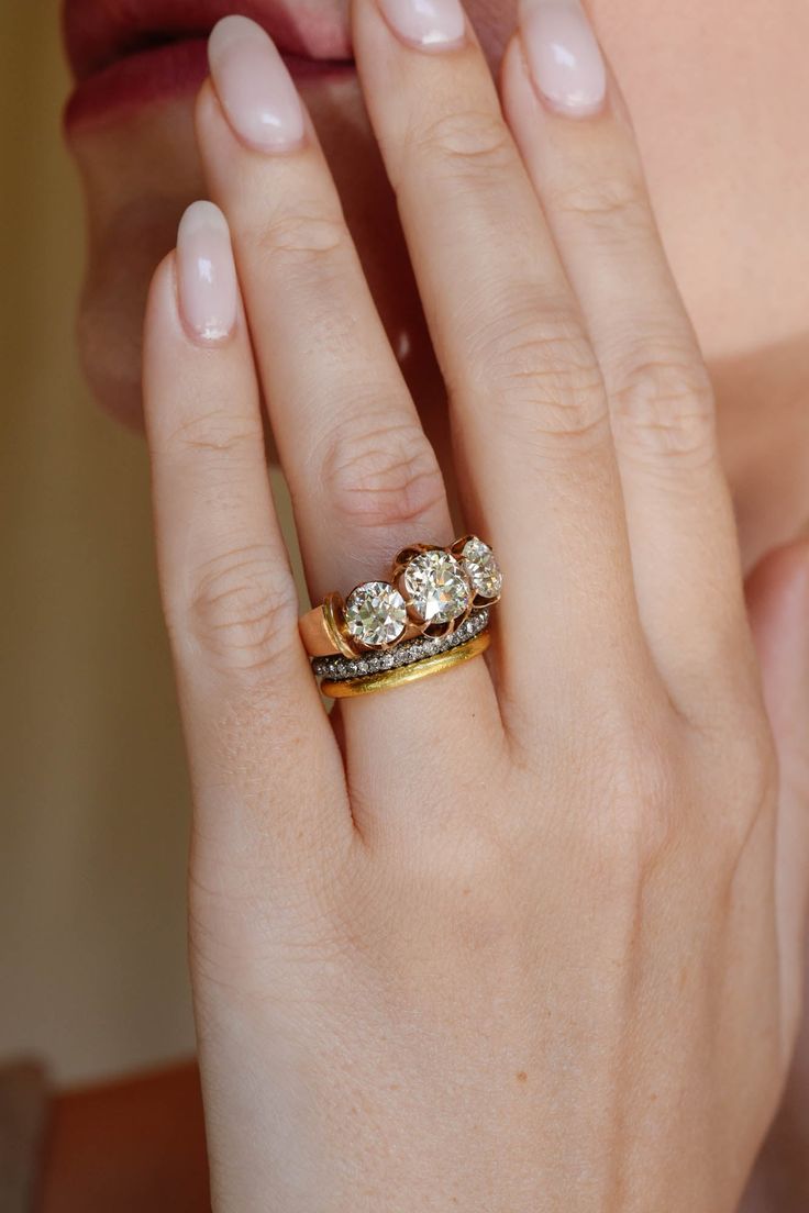 a woman's hand with a ring on it and two diamonds in the middle