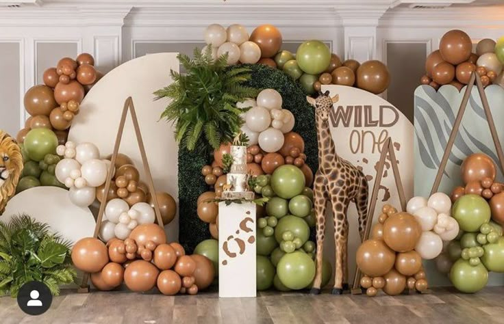 an animal themed backdrop with balloons and jungle animals on the wall, including a giraffe