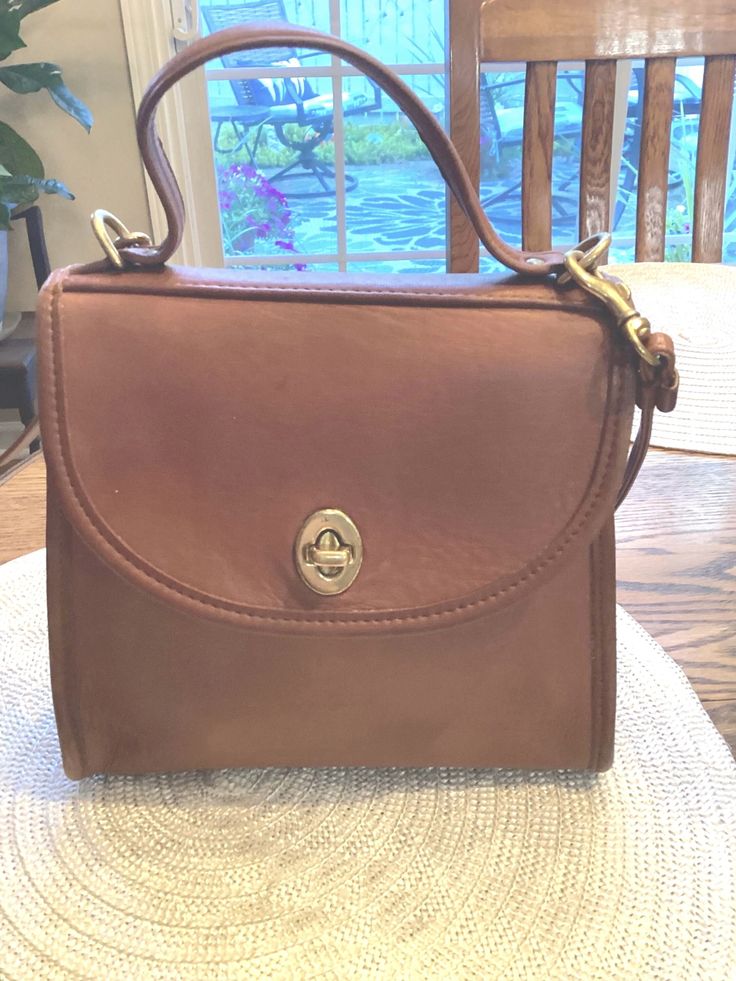 Vintage Coach Leather Regina 9983 Bag British Leather British Tan crossbody bag with a top carrying handle and detachable crossbody strap. It features a brass kiss turn and brass two D rings for strap and brass hooks on either side. This purse has a beautiful suede interior , a back wide slot the full length of a person and an interior full length zipper pocketThere is a small spot of ink on the front, slight marks on the back of purse and some wear on the corner rim of purse. I have taken a pic Classic Gold Satchel With Brass Hardware, Formal Satchel With Brass Hardware And Tote Shape, Formal Tote Satchel With Brass Hardware, Formal Satchel Tote With Brass Hardware, Formal Satchel With Brass Hardware, Classic Shoulder Bag With Brass Hardware And Top Handle, Classic Top Handle Shoulder Bag With Brass Hardware, Classic Shoulder Bag With Top Handle And Brass Hardware, Formal Crossbody Flap Bag With Brass Hardware