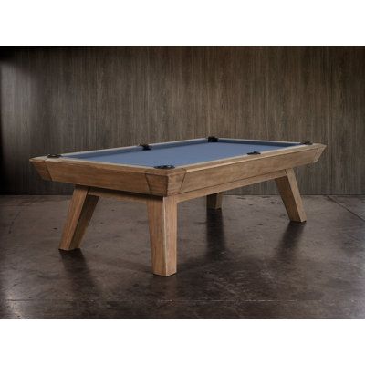 a pool table sitting on top of a cement floor next to a wooden paneled wall