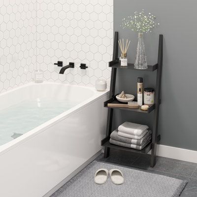 a bathroom with gray walls and white tile flooring, a black shelf holding towels