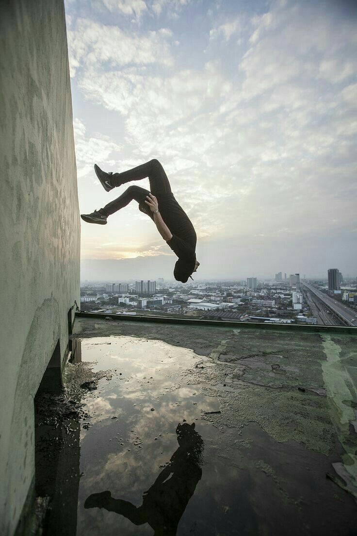 a person jumping into the air on top of a building