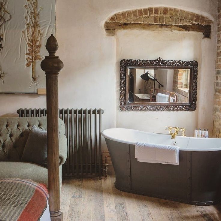 an old fashioned bathtub is in the middle of a room with exposed brick walls