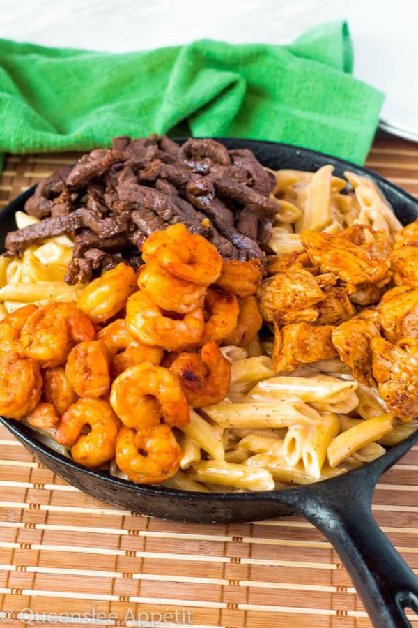 a skillet filled with pasta, meat and other foods on top of a bamboo mat