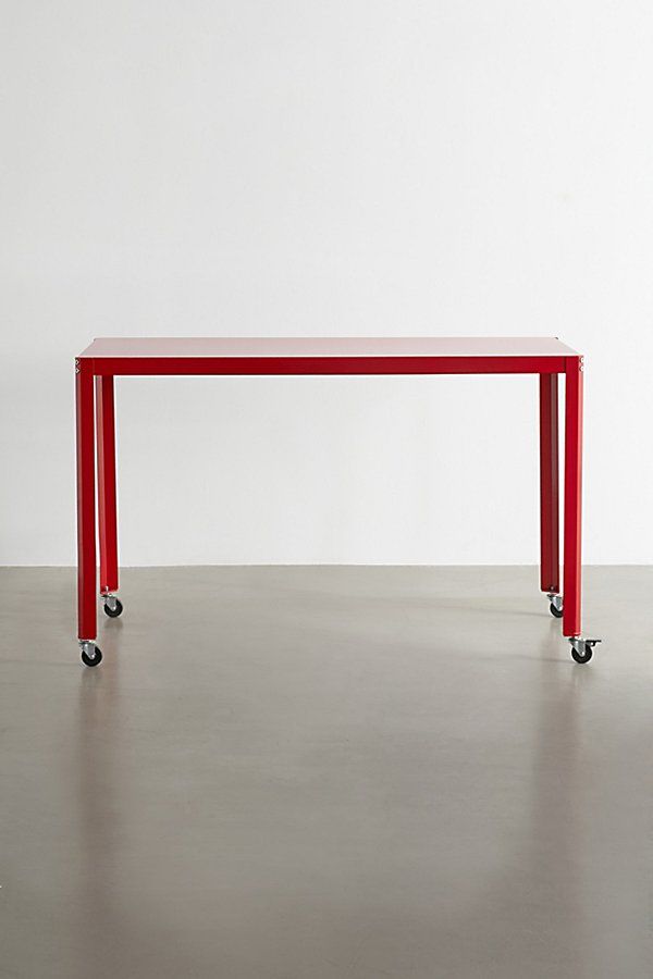 a red table sitting on top of a hard wood floor next to a white wall