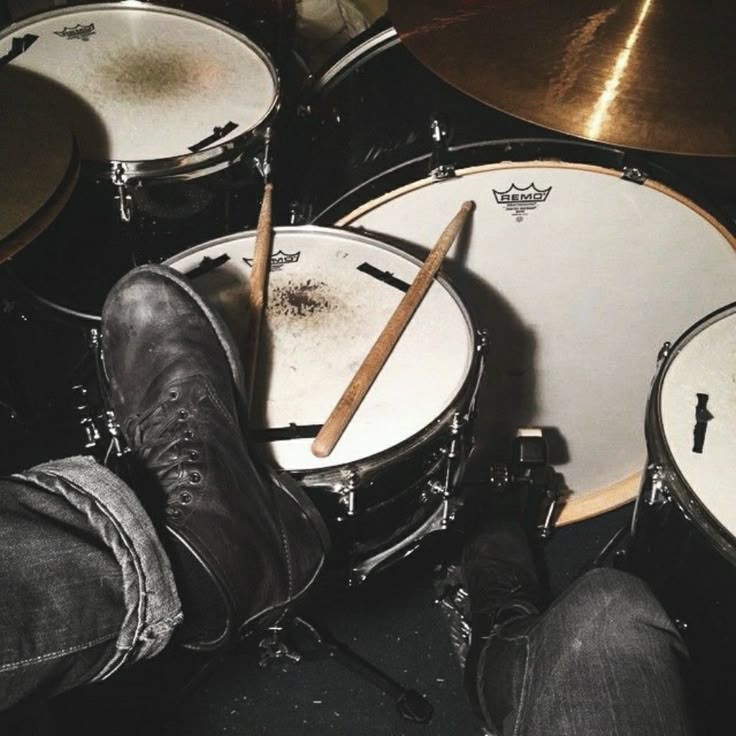 a pair of legs and boots are next to a drum set