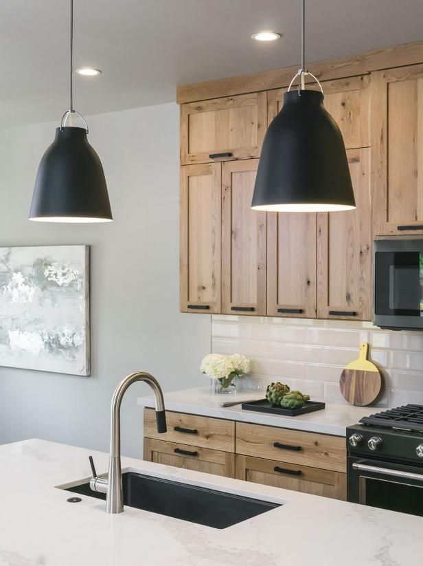 a kitchen with two black lights hanging over the stove top and an island in front of it