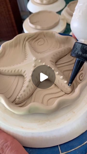 a person is using a paintbrush to decorate pottery