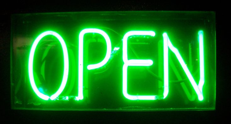 an open sign lit up in the dark with neon lights on it's sides