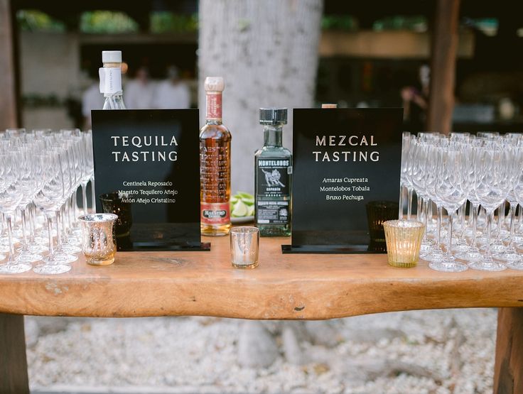 there are many wine glasses and bottles on the table with labels that say mezcal tasting