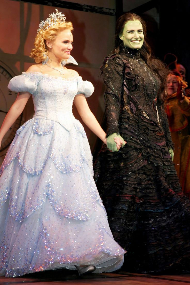 two people dressed in costumes on stage with one holding the hand of another person's hand