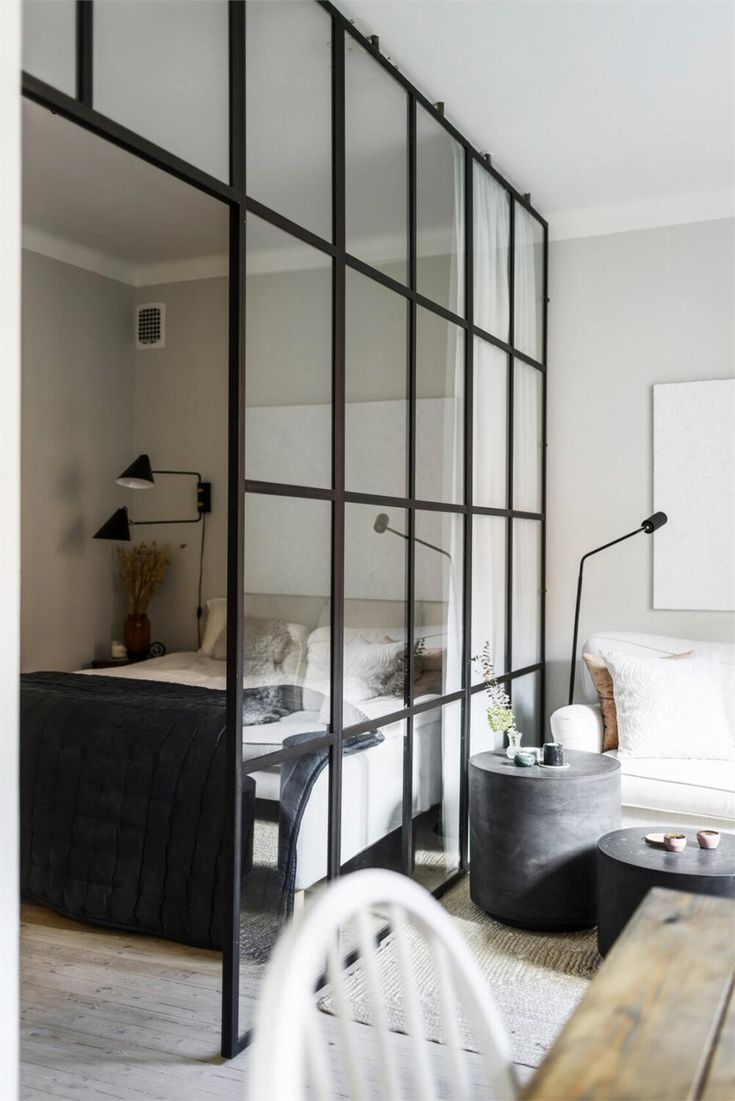 a room with a bed, table and chair in it next to a glass wall