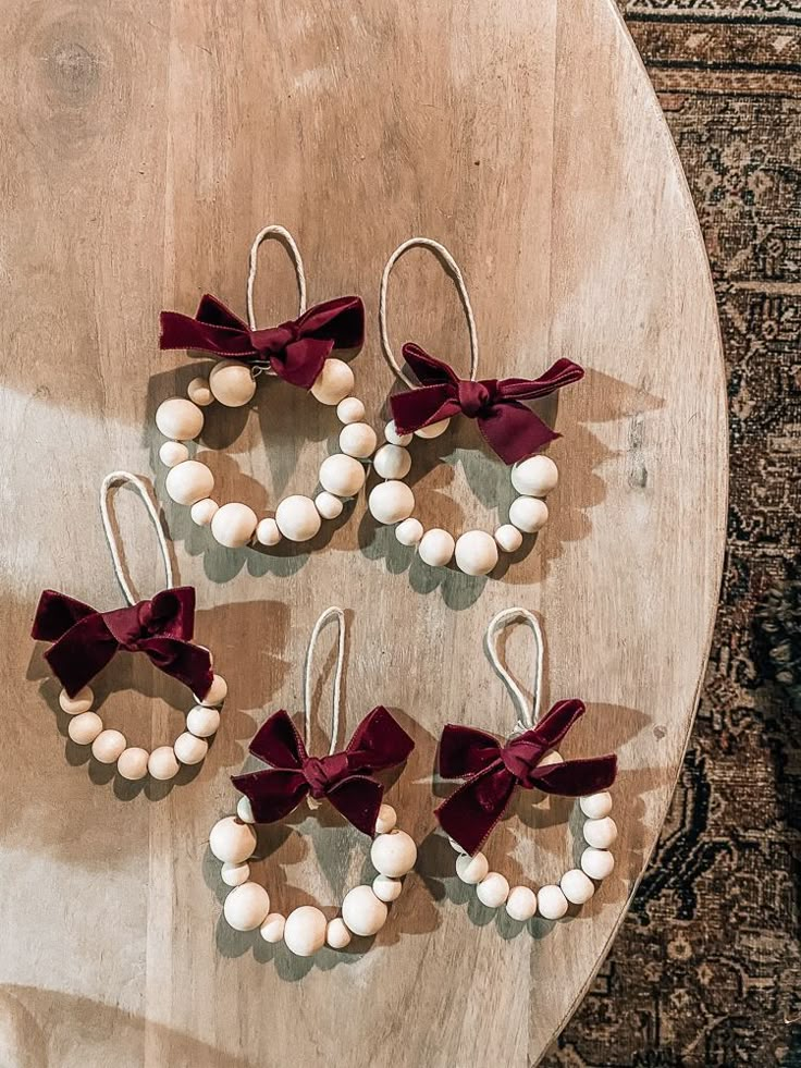 four pairs of earrings with bows on them sitting on top of a wooden table next to a rug