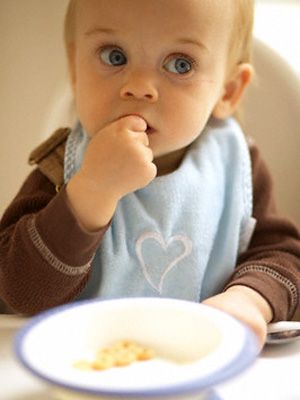 a baby sitting at a table eating food