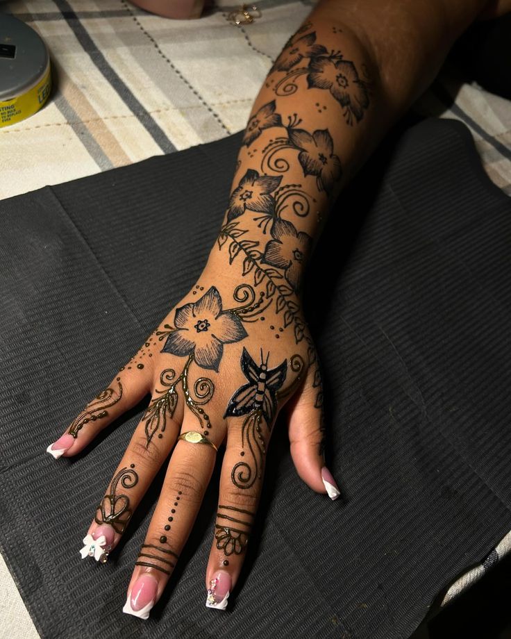 a woman's hand with tattoos on it sitting on top of a black mat