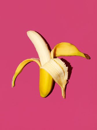 a half peeled banana on a pink background