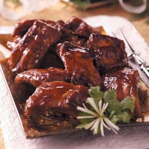 a plate full of ribs covered in sauce and garnished with parsley on the side