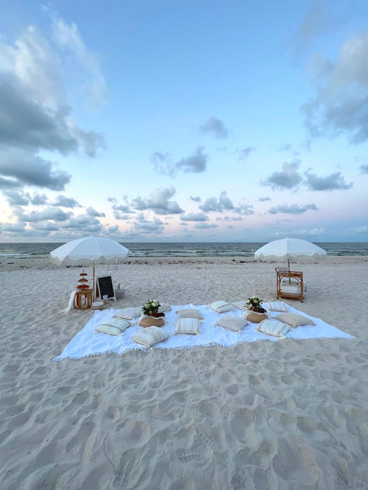 an empty beach with white umbrellas and pillows on the sand at sunset or dawn