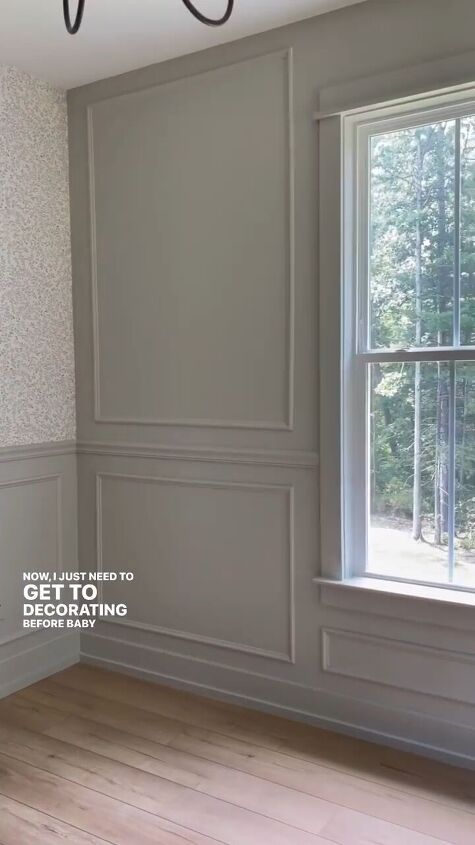 an empty room with wood flooring and gray wallpaper on the walls, along with a chandelier