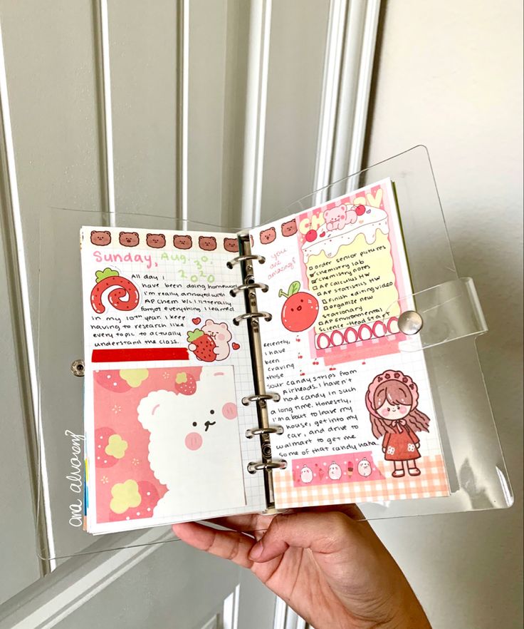 a hand holding an open planner book in front of a door